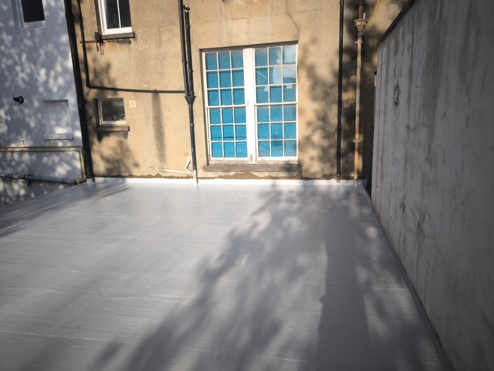 Flat roof refurbished with a light-grey PMMA system