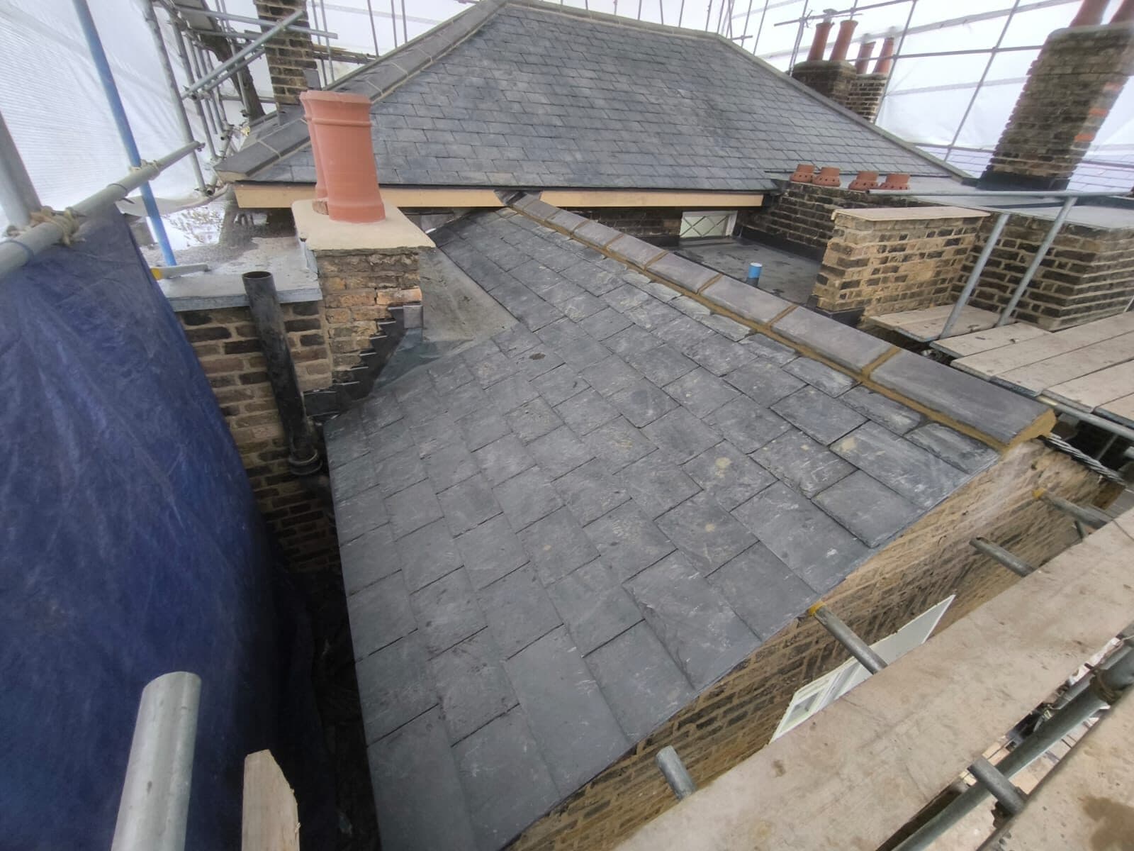 Stepped flashing detailed around a chimney on a slate roof